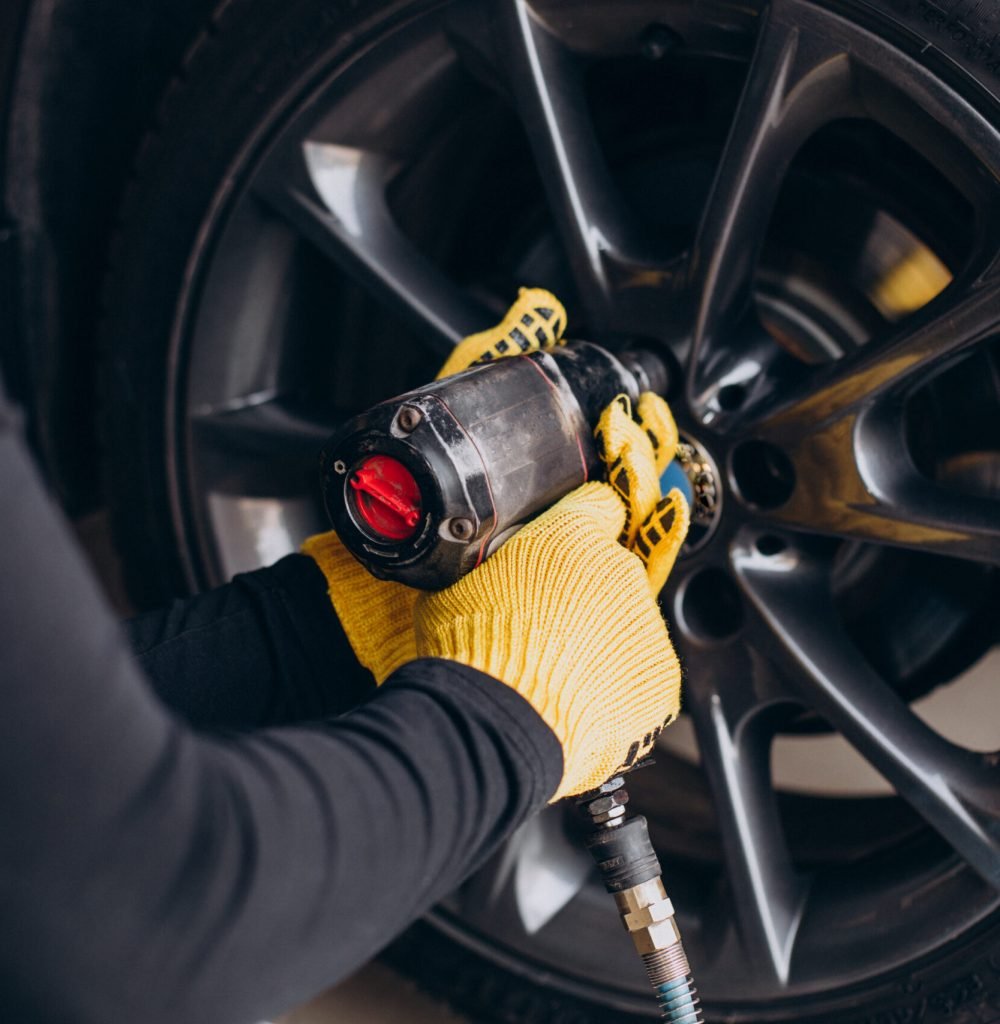 Car mechanic changing wheels in car