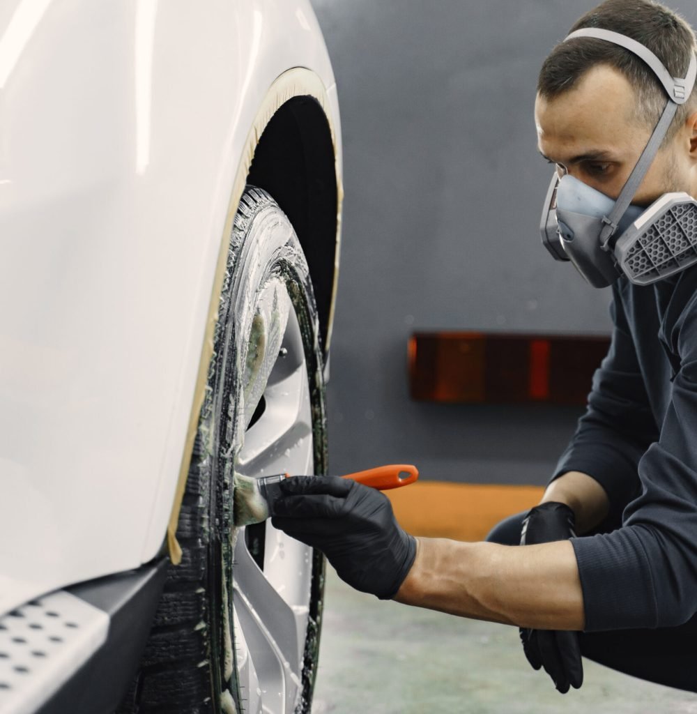 Men's hands are cleaning wheels. Hand of man holding sponge and foam washing wheel. Worker in a black uniform.